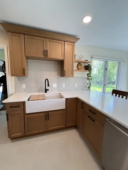 Oak shaker cabinets, white farmhouse sink, black faucet and quartz peninsula