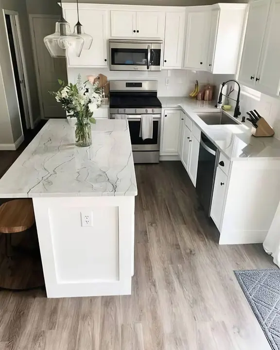 White shaker kitchen with marble-look island and glass pendants