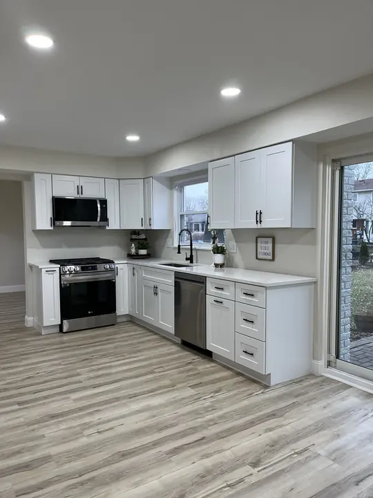 White shaker kitchen with quartz counters and LVP flooring